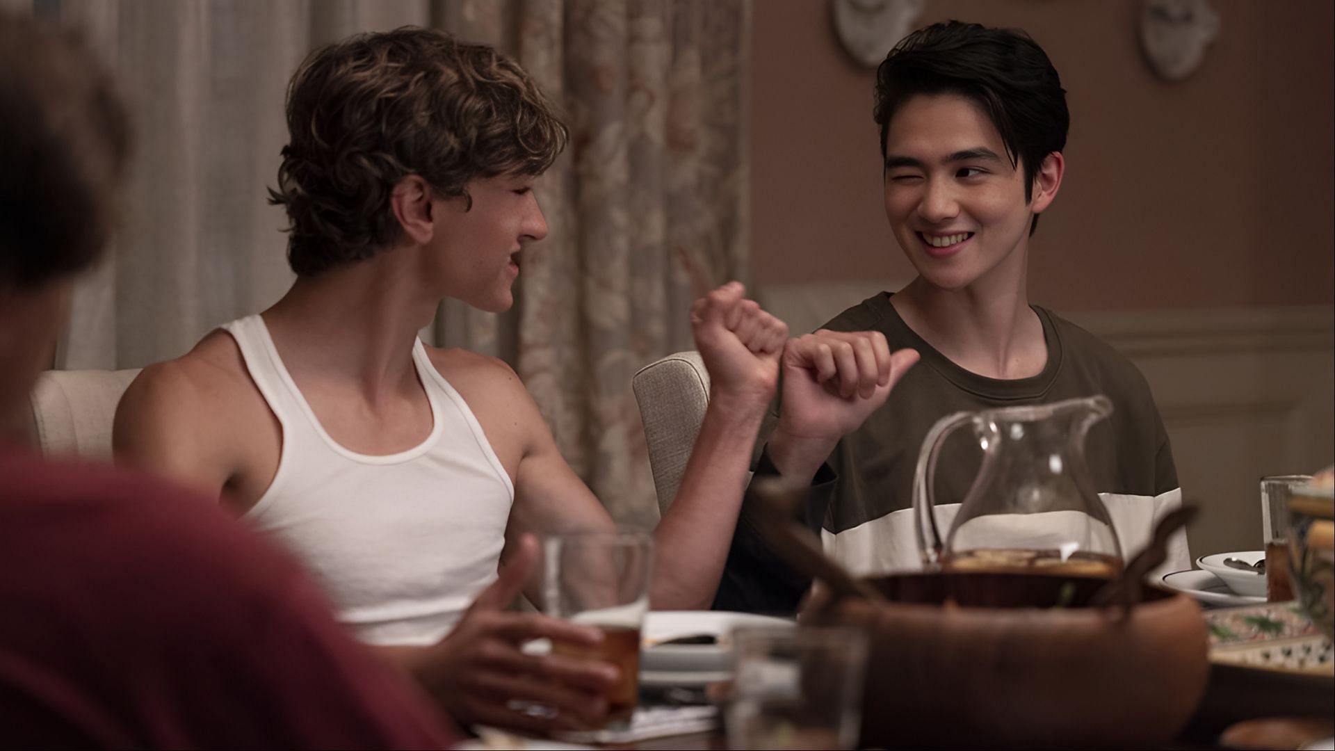 Jeremiah and Steven share a light-hearted moment at the dinner table in The Summer I Turned Pretty season 3, highlighting their close bond. (Image via Amazon Prime)